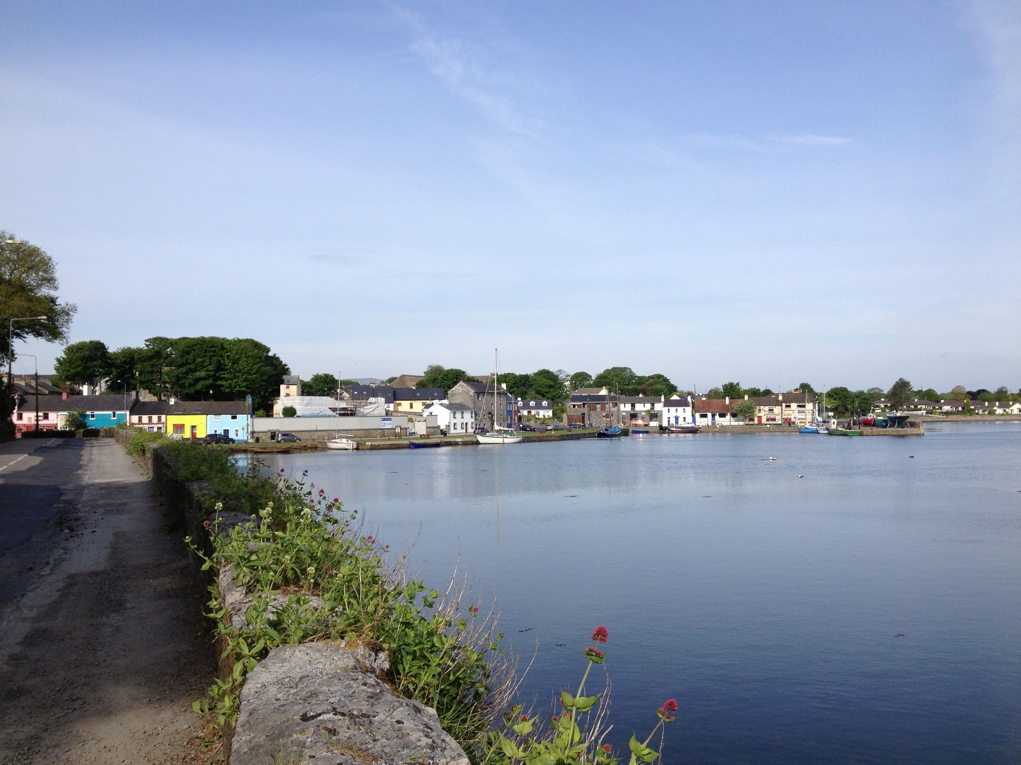 A coastal town with a calm harbor, colorful houses, and a clear sky.