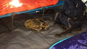 Una carpa con una zona para dormir, un par de zapatos y una mochila.