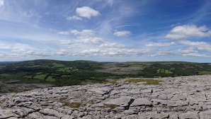 A panoramic view of a rocky landscape with distant hills and a clear sky. - Burren Bushcraft - Camping & Adventures (Carran)