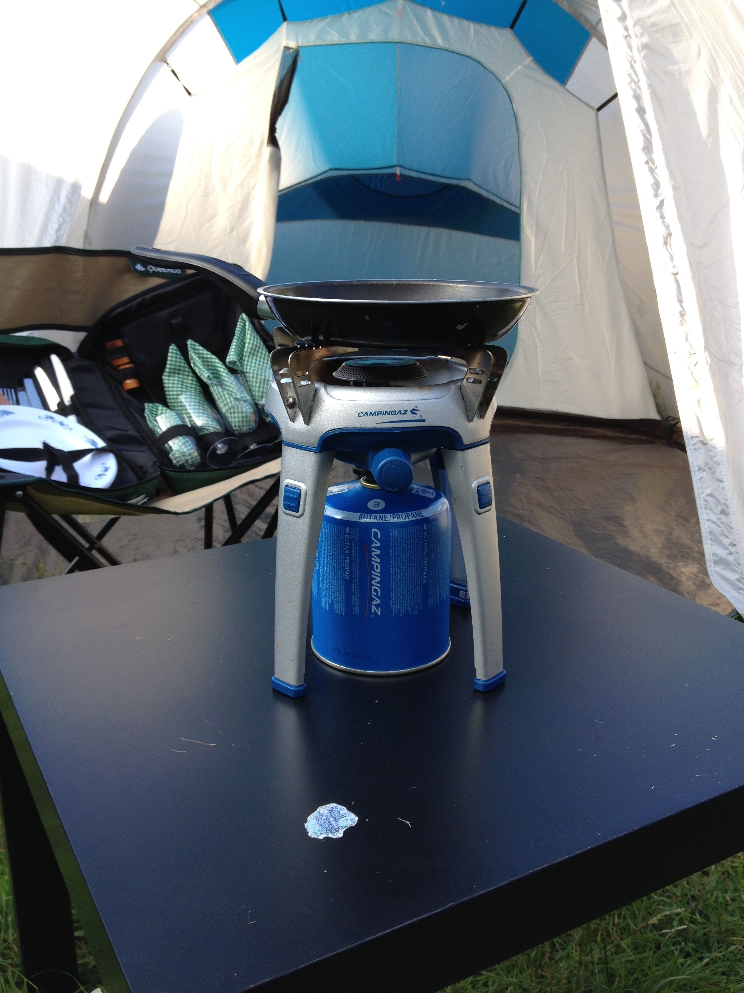 A camping stove with a propane canister on a table.