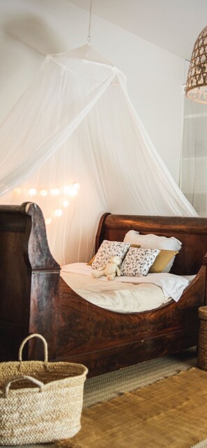 A wooden bed with a white canopy, a bedside basket, and a wall-mounted light fixture. - Domaine de la Partoucie (Confolens)