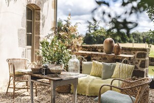 A rustic outdoor seating area with wicker furniture, a stone wall, and a glass jar centerpiece.