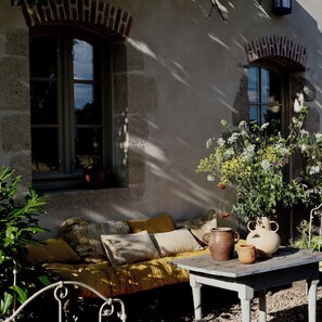 A cozy outdoor seating area with a table, cushions, and a potted plant. - Domaine de la Partoucie (Confolens)