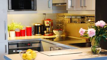 Een moderne keuken met roestvrijstalen apparatuur, een koffiezetapparaat en een vaas met bloemen op het aanrecht.
