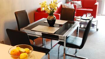 A dining area with a glass table, black chairs, and a bowl of fruit on the table.