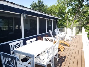 A covered outdoor deck with white furniture, including a table and chairs, and a wooden deck. - Lakefront - Gentle Slope to Water - Sleeps 18 (Shell Knob)