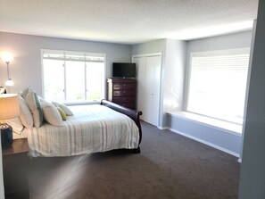 A bedroom with a bed, dresser, and a TV on top. There are windows with blinds and a lamp on the side table. - Lakefront - Gentle Slope to Water - Sleeps 18 (Shell Knob)