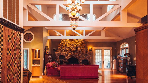Amplia sala de estar con un sofá rojo, una chimenea de piedra y una escalera de madera.