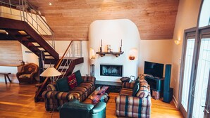 Amplia sala de estar con chimenea, una escalera y un televisor.