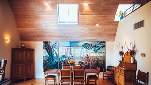 Un comedor con techo de madera, un ventanal grande y un mural de plantas tropicales.
