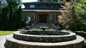 Una escalera de piedra conduce a una casa de piedra con un gran puerta principal y ventanas.