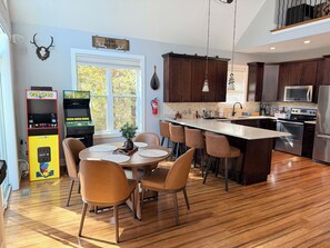 Une cuisine moderne avec des meubles en bois, un îlot central et un coin repas comprenant une table et des chaises.