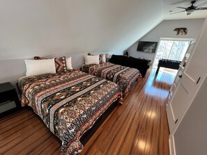 Une chambre avec deux lits, un ventilateur de plafond et une vue sur l’extérieur.