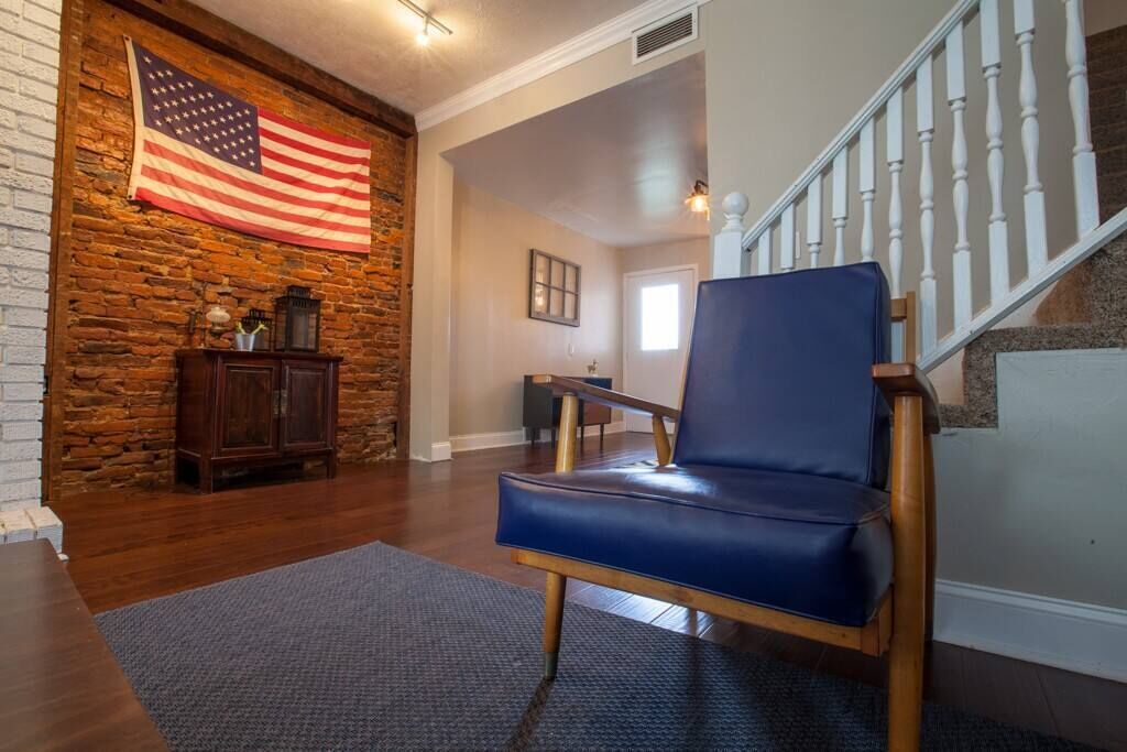 Ein Zimmer mit einem blauen Ledersessel, einer Steinsäule, einer amerikanischen Flagge und einer Treppe.
