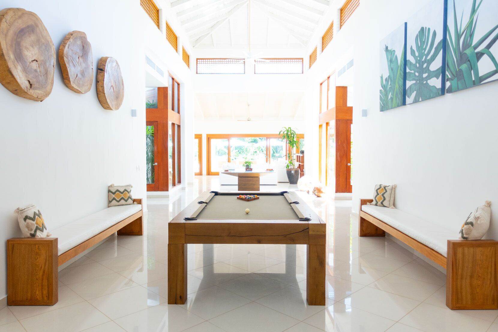 Een moderne kamer met een pooltafel, houten banken en een groot raam.
