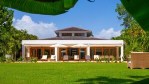 A two-story house with a covered patio area, large windows, and a well-maintained lawn.