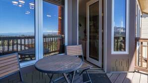 Ein Balkon mit Tisch und Stühlen, eine Schiebeglastür und Blick auf die Berge.