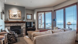 Ein Wohnzimmer mit Kamin, einer Couch, einem gemusterten Sessel und einem Fernseher.