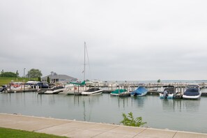 Boats dock at the marina, surrounded by a grassy area and a building.