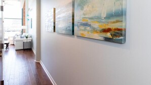 A hallway with wooden flooring and a white wall with two paintings. - Spectacular Waterfront Condo Retreat For 6 w/ Cedar Point View! (Sandusky)