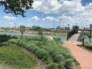 A boardwalk leading to a marina with boats, a signboard, and a clear sky. - Spectacular Waterfront Condo Retreat For 6 w/ Cedar Point View! (Sandusky)