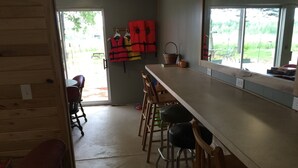 Een keuken met een lange aanrecht, houten stoelen en uitzicht op de omgeving.