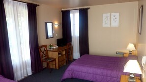 Habitación de hotel con dos camas, un escritorio, una computadora, una silla y una lámpara.