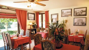 Comedor con mesas dispuestas para cuatro, manteles rojos y sillas con tapicería floral.