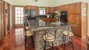 Un'ampia cucina con una grande isola, mobili in legno e una parete a contrasto in pietra.