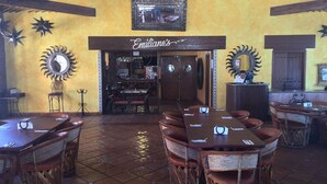 A restaurant with a yellow wall, a sign reading "Emiliano's", and a large mirror on the wall. - Beach Front Convenience..Steps to the Beach and Pool !  (Puerto penasco)