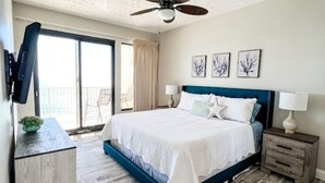 Ein Schlafzimmer mit einem Bett, einem Deckenventilator, einem an der Wand montierten Fernseher und einem Balkon mit Blick.