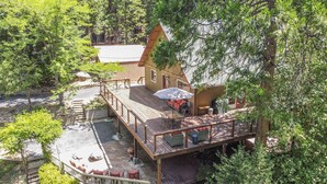 A wooden deck with outdoor seating, a small building with a red roof, and a staircase leading to a higher deck. - Gorgeous Home on 6 Scenic & Private Acres-Close to many lakes and rivers (Pioneer)
