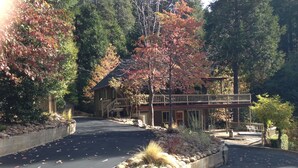 A two-story house with a covered porch and a stone retaining wall. - Gorgeous Home on 6 Scenic & Private Acres-Close to many lakes and rivers (Pioneer)