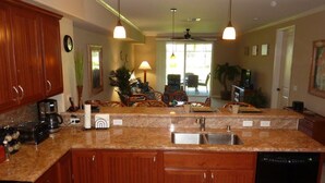 A kitchen with granite countertops, wooden cabinets, a dishwasher, and a coffee maker.