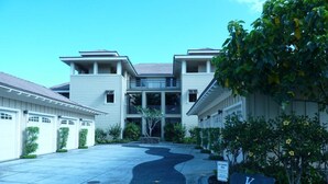 A modern building with a central entrance, multiple garage doors, and a landscaped driveway.