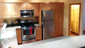 A kitchen with wooden cabinets, stainless steel appliances, and a countertop. - 3BR Townhouse - Your Home Away from Home (mammoth lakes)