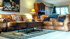 A spacious living room with a high ceiling, a wooden balcony, a large painting, and a fireplace. - 3BR Townhouse - Your Home Away from Home (mammoth lakes)