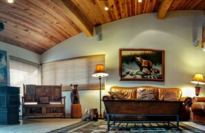 A cozy living room with a wooden ceiling, a large painting of a bear, a leather sofa, and two lamps. - 3BR Townhouse - Your Home Away from Home (mammoth lakes)