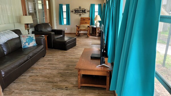 A living room with a brown leather sofa, a wooden coffee table, and a wooden rocking chair.