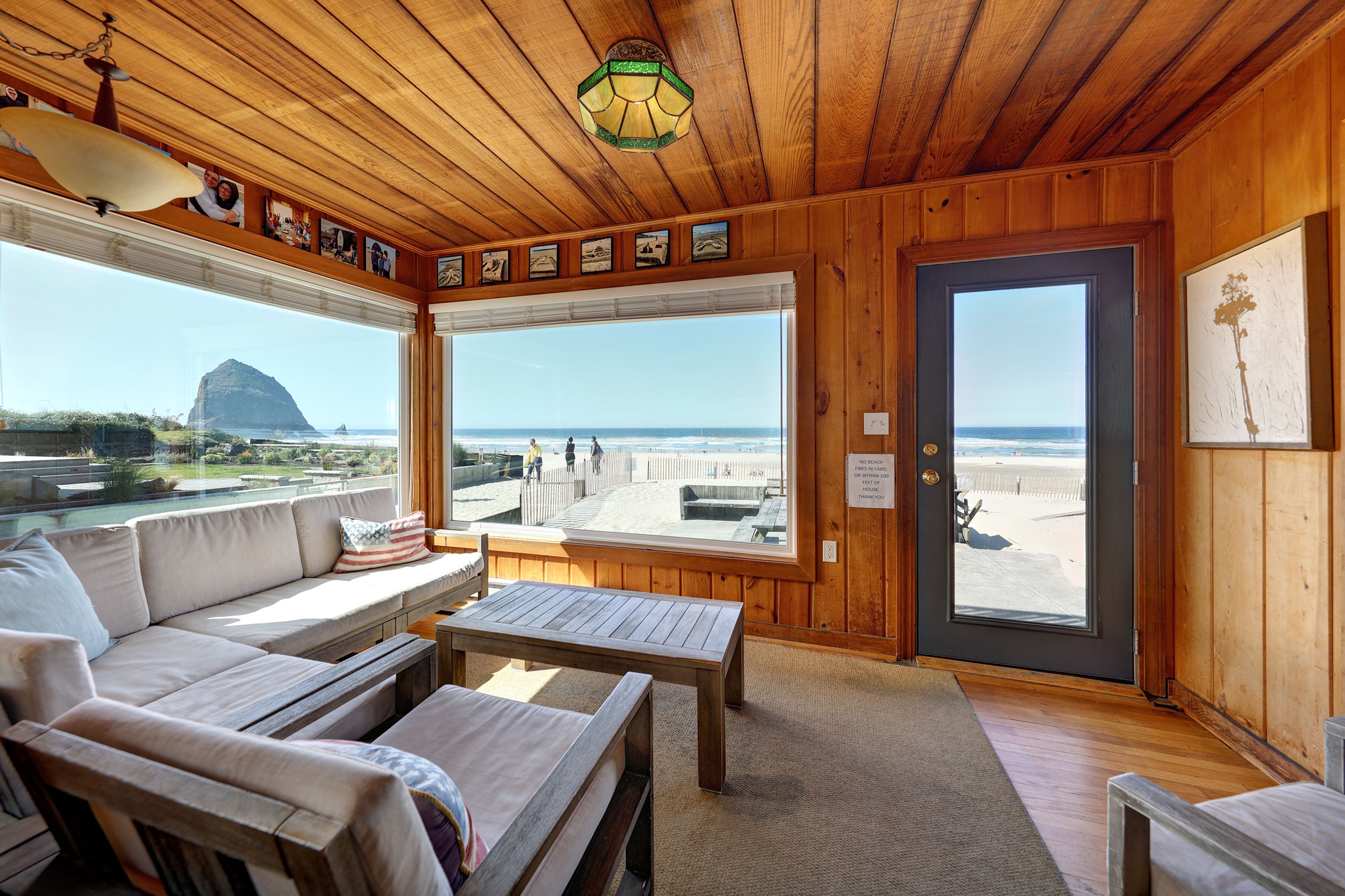 Un intérieur en bois avec un canapé, une table et une vue sur la plage.