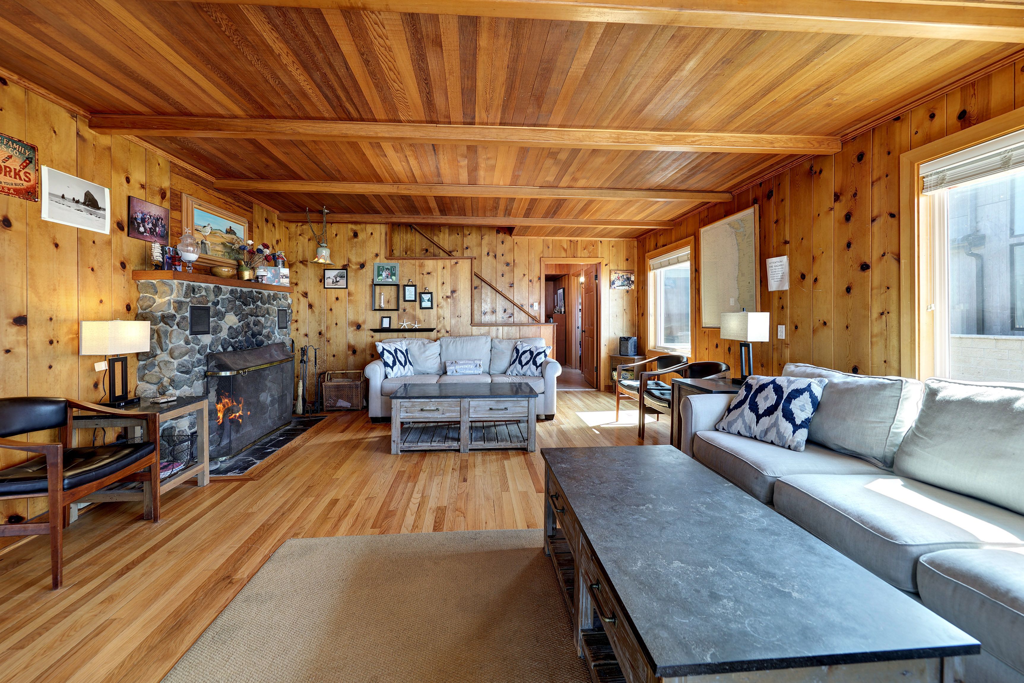 L’intérieur chaleureux d’un chalet avec une cheminée en pierre, des murs en bois, un canapé et une table à manger.