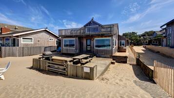 Une propriété située en bord de mer, dotée d’une terrasse en bois, d’un barbecue et offrant une vue sur l’océan.