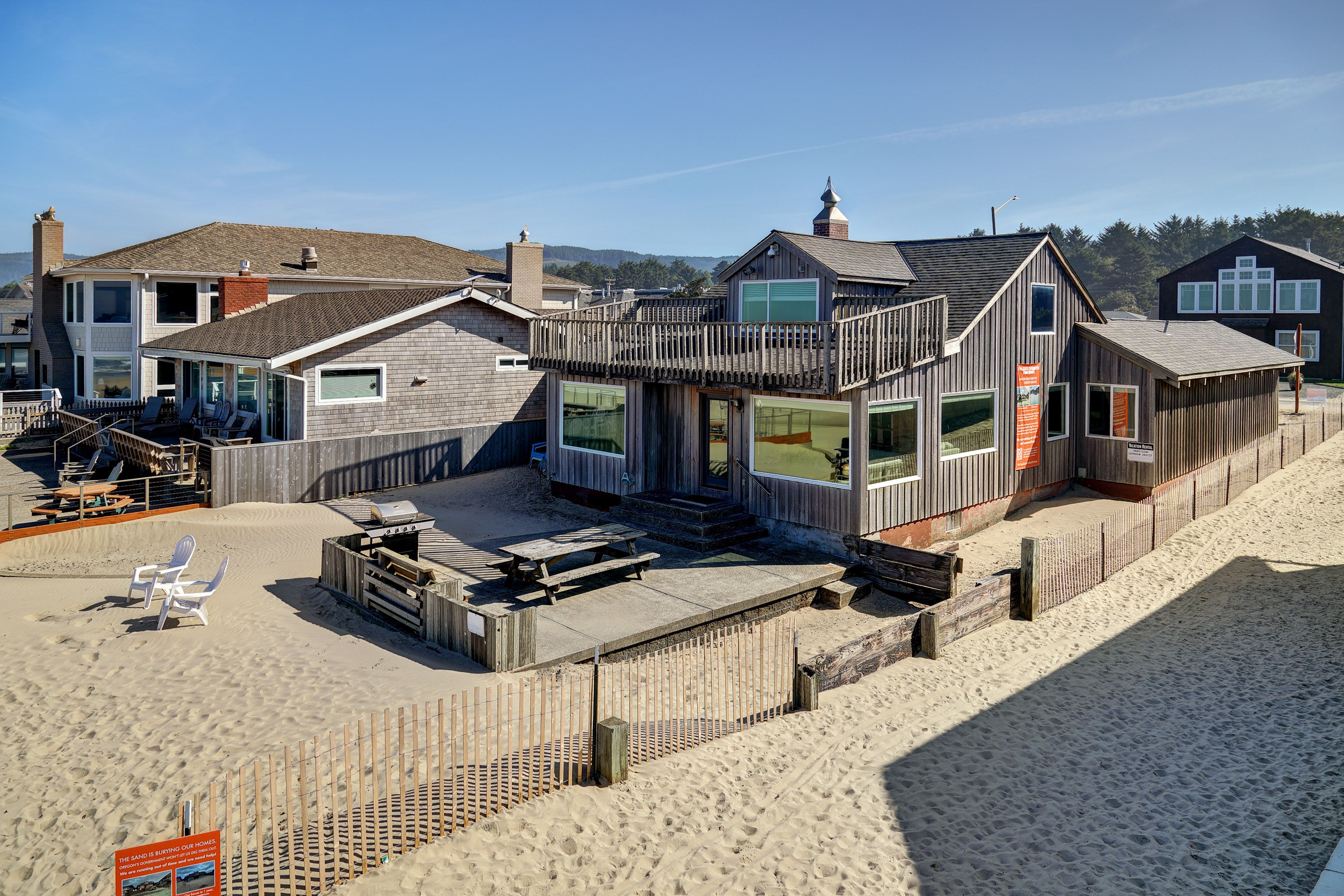 A beachfront property with a wooden deck, outdoor seating, and a view of the ocean.
