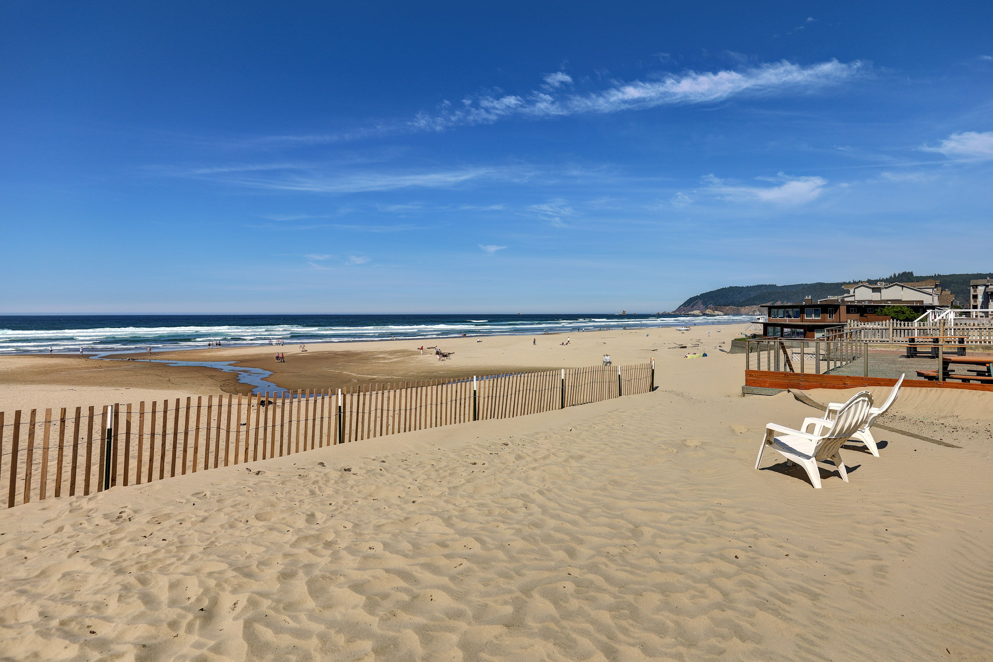 A beach with a wooden fence, a lifeguard tower, and a bench.