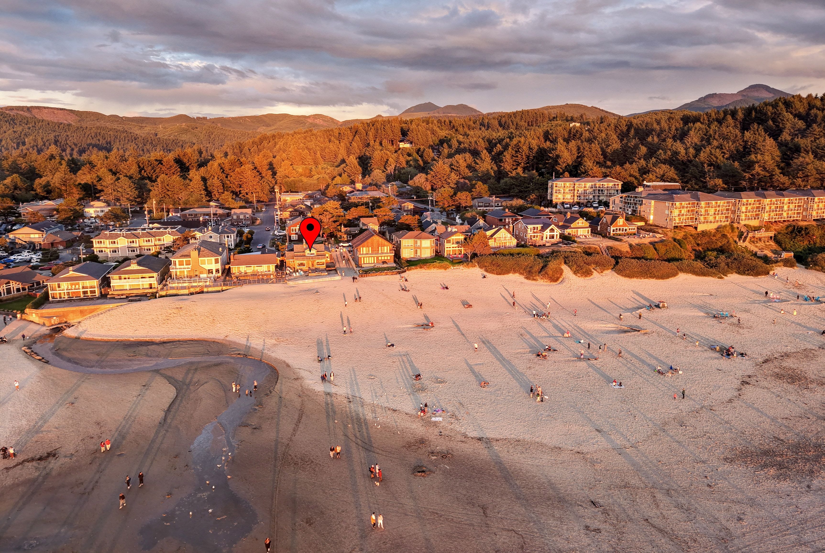 A coastal town with a beach, houses, and a mountain range in the background.