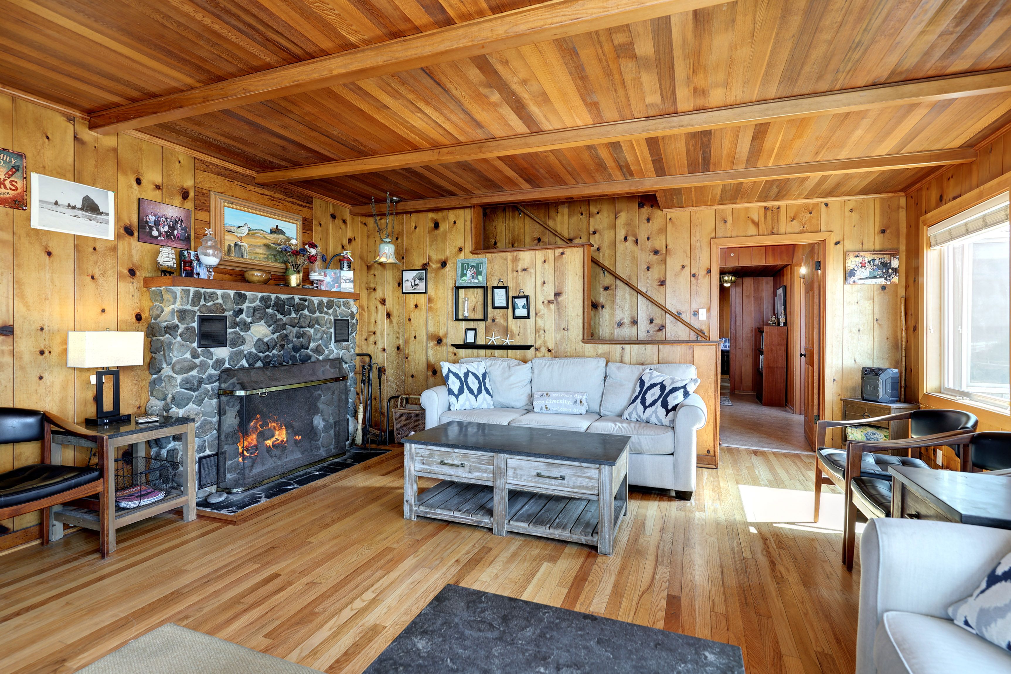 L’intérieur d’un chalet accueillant, avec une cheminée en pierre, des murs en bois, un canapé et un coin repas.