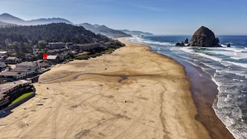 Une ville côtière dotée d’une plage de sable, d’un promontoire rocheux et d’une colline boisée.