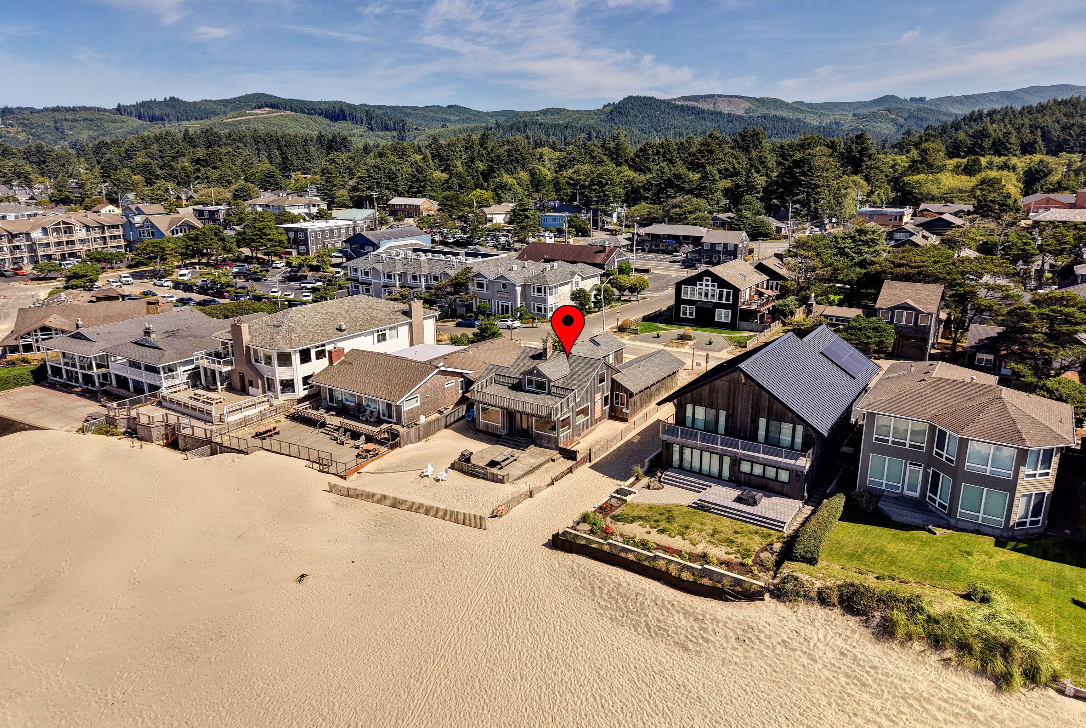 Une zone résidentielle côtière avec des maisons, une plage de sable et un repère géographique de couleur rouge.