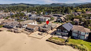 Une zone résidentielle côtière avec des maisons, une plage de sable et un repère géographique de couleur rouge.