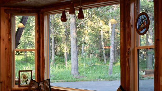 A cabin interior with large windows, wooden walls, and a bench by the window.